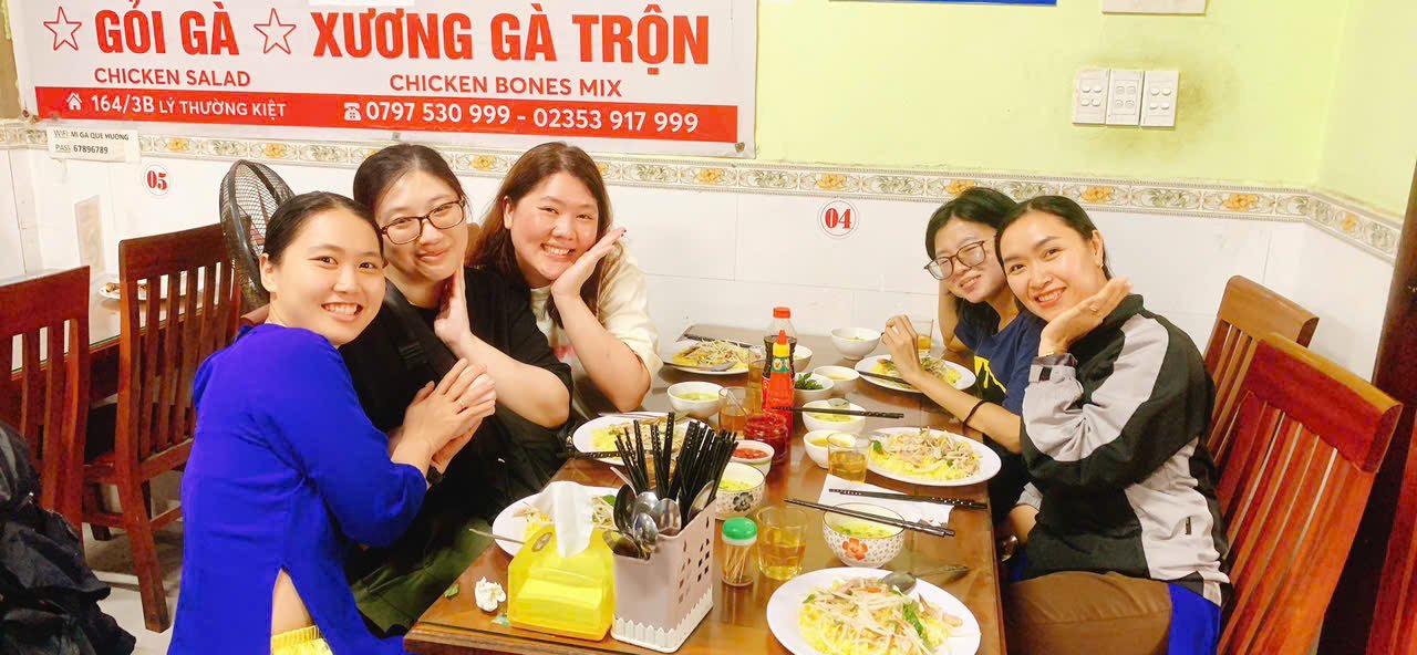 地元のレストランで食事を楽しむ旅行者とアオザイのガイド